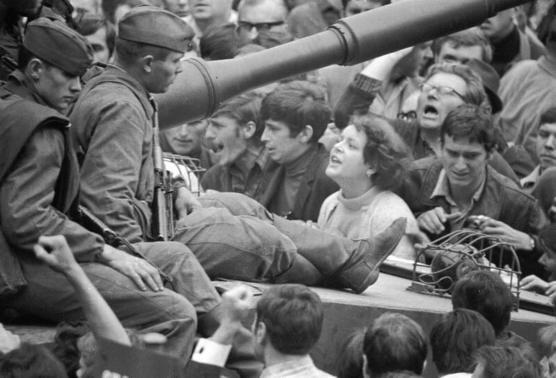 historia completa de eslovaquia: foto en blanco y negro en que se ven dos soldados sovieticos sentados encima de un tanque rodeado por multitud de manifestantes checos entre los que destaca una mujer gritandoles apoyada en el tanque