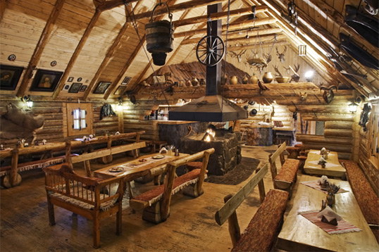 interior de una koliba o restaurante tradicional de madera con el techo en V invertida y todo el interior decorado con muebles de madera, y una hoguera en el centro, el mejor sitio para disfrutar de una buena comida tipica de eslovaquia y de toda su gastronomia