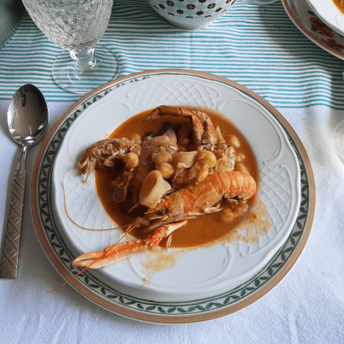 Plato de caldereta de garbanzos y marisco, en que se ve una cigala, un trozo de cangrejo, sepia y otros ingredientes