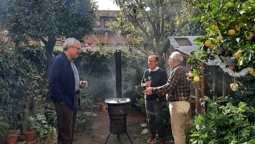amigos de unos 60 anos charlando alrededor de la kotlina, la cocina de lena para exterior