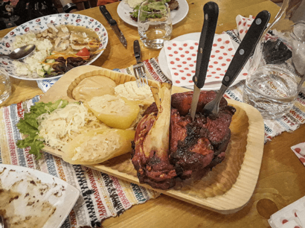 gastronomia y platos tipicos de eslovaquia: codillo de cerdo asado en un plato de madera acompanado de col fermentada y mostaza